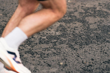 Pernas de corredor em movimento no asfalto mostrando a pisada durante a corrida